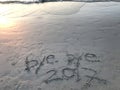 Handwritten words Ã¢â¬Åbye bye 2017Ã¢â¬Â on the beach with many footprints